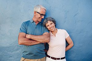 Older couple posing together in front of a blue wall