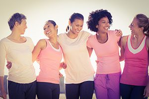 A group of women in workout clothes standing together smiling at each other